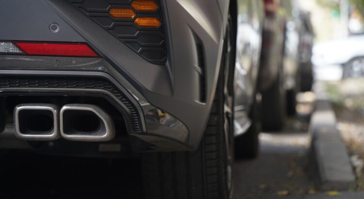 Image of an exhaust pipe on a car parked on a street.