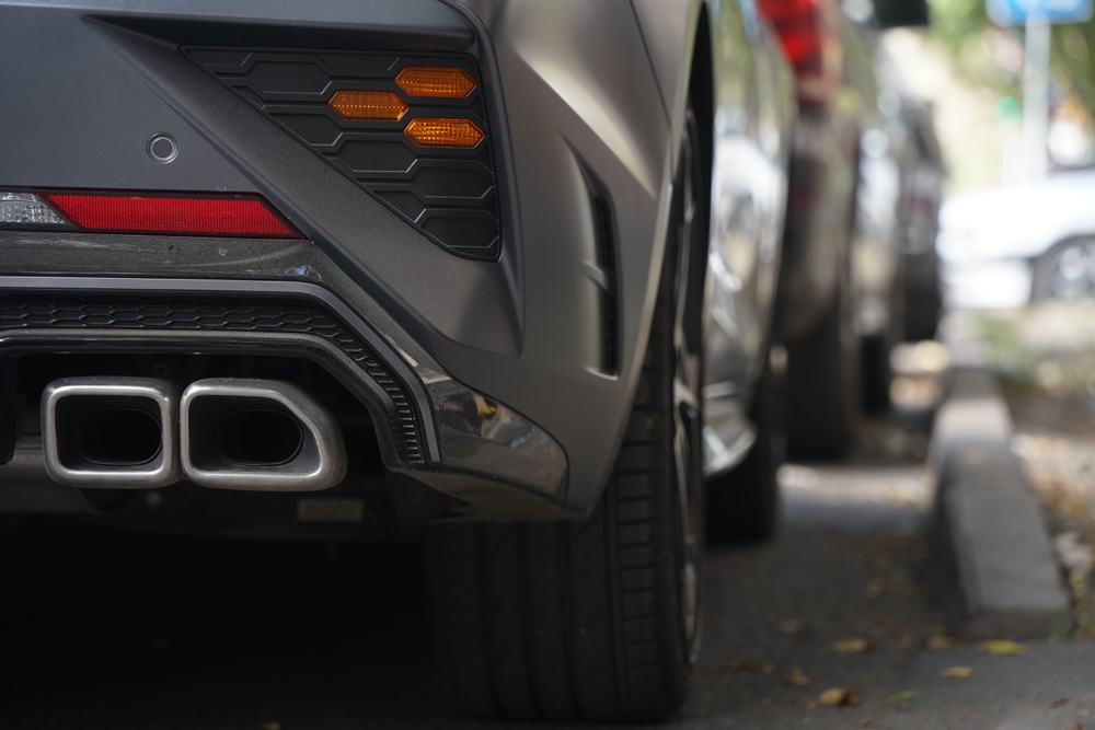 Image of an exhaust pipe on a car parked on a street.